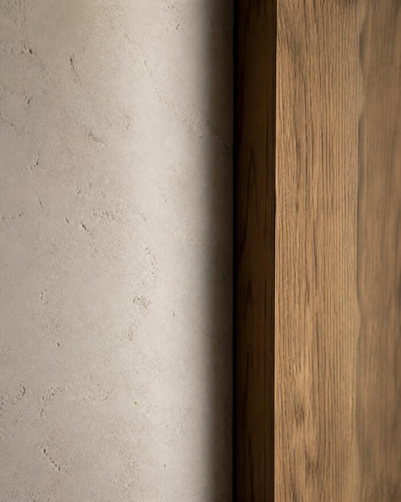 Detail of hand-finished limestone meeting an oak edge in raking light